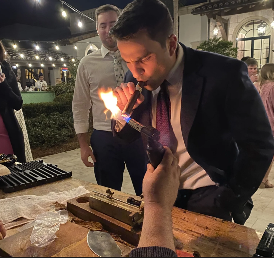 Cigar lighting at an evening event, with the rolling table and tools visible